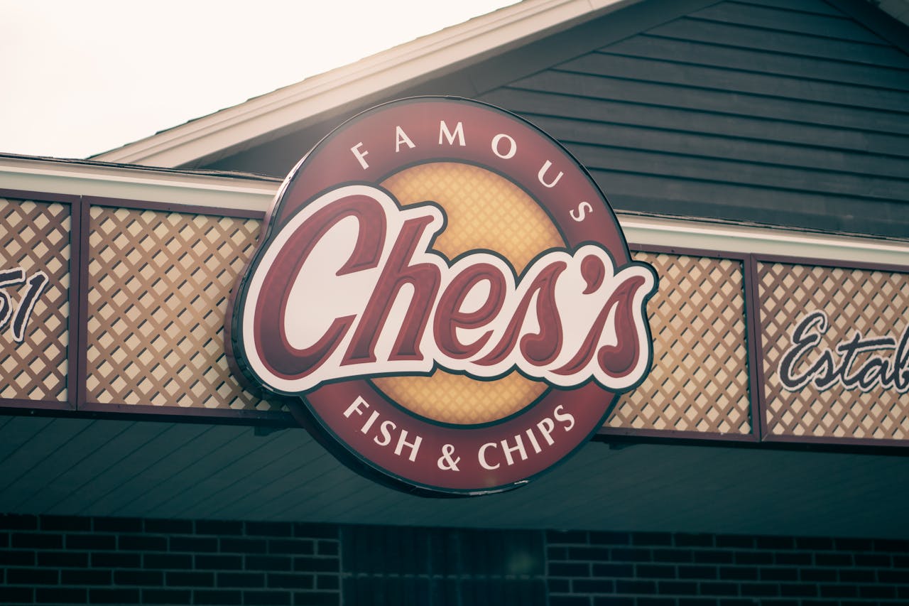 Creative design of signboard with Famous Fish and Chips inscriptions on wall of restaurant building in city